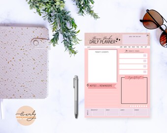 May include: Pink daily planner with the text "Boss Babe Daily Planner" in black script font. The planner has sections for goals, events, tasks, notes, reminders, and meals.