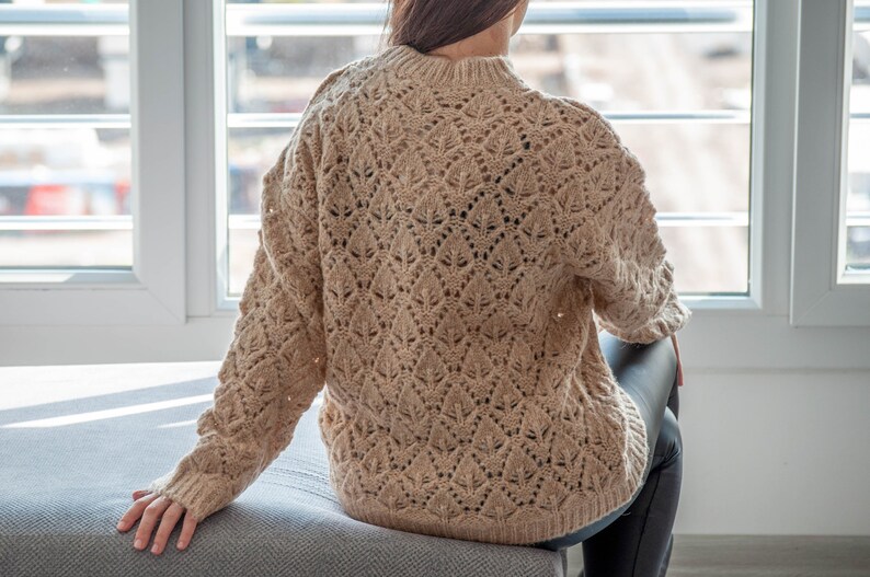 May include: A beige knitted sweater with a delicate openwork pattern.