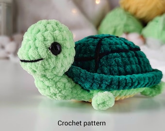 May include: A crocheted green turtle with a dark green shell and black eyes. The turtle is lying on a white surface. Crochet pattern.