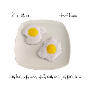 May include: Two felt fried egg shapes on a white plate. The eggs are white with yellow centres. The text "2 shapes" and "4x4 hoop" is above the plate. The text "pes, hus, vip, xxx, vp3, dst, exp, jef, pec, sew" is below the plate.