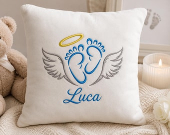May include: A square white throw pillow featuring centered embroidery of two blue baby footprints with grey wings on either side and a yellow halo above. The name Luca is embroidered in blue script lettering below the footprints.