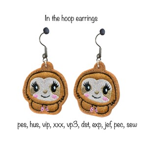 May include: A pair of brown sloth earrings with pink accents. The earrings are made of felt and are designed to be worn in the hoop.