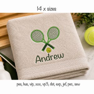 May include: A beige towel featuring an embroidered design of two crossed green tennis rackets and a yellow tennis ball above the name Andrew in green script. The text 14 x sizes and file formats pes, hus, vip, xxx, vp3, dst, exp, jef, pec, sew appear.