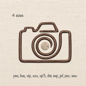 May include: An embroidery design of a camera outlined in dark brown thread with a spiral lens and a small beige center circle. The text 4 sizes appears above the camera, and the text pes, hus, vip, xxx, vp3, dst, exp, jef, pec, sew appears below.