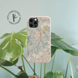 May include: A rectangular phone case featuring a light sage green background with a repeating pattern of small pink flowers and greyish-blue foliage. A circular logo in the top left corner reads 100% COMPOSTABLE BAMBOO FIBER.