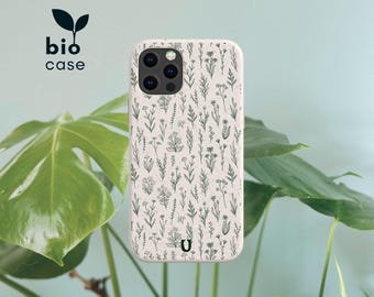 May include: A speckled off-white phone case featuring a dark green botanical pattern of various wildflowers and stems. The case includes a camera cutout and the text bio case with a leaf icon, along with a small U logo at the bottom center.