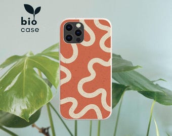 May include: A phone case featuring a terracotta orange background with a speckled texture and a continuous, winding cream-colored line pattern. The case has a camera cutout and the text bio case with a small leaf icon printed in the upper left corner.