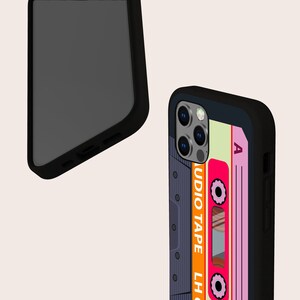 May include: Black phone case with a retro cassette tape design. The case features a pink and orange cassette tape with the text "AUDIO TAPE LH" and "A" on the case.