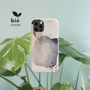 May include: A bio case phone cover featuring an abstract watercolor design with soft beige, grey, and dark blue organic shapes. The surface has a speckled texture and includes small black dash marks. The text bio case is printed in black.