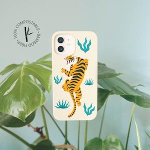 May include: A white phone case with a tiger illustration and green foliage. The case is made from 100% bamboo fiber and is compostable.