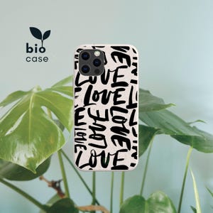 May include: A phone case with a speckled off-white base featuring a repeating black brushstroke pattern of the word LOVE. The case has a camera cutout and the text bio case with a small leaf icon is printed in the upper left corner of the image.