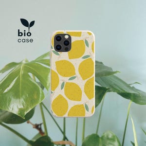 May include: A phone case with a cream-colored background featuring a repeating pattern of yellow lemons and small green leaves. The case has a cutout for a multi-lens camera system. The text bio case with a small leaf icon is visible.