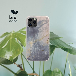 May include: A rectangular phone case featuring a grey and white marble pattern with gold-colored veining accents. The case has a camera cutout at the top left corner. The text bio case with a small leaf icon is printed in black above the phone case.