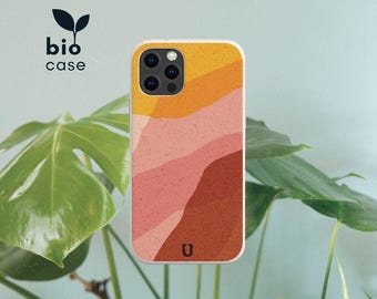 Puede incluir: Una funda para teléfono con un diseño de paisaje abstracto y texturizado con ondas superpuestas de amarillo, melocotón, rosa y naranja terracota. La funda incluye un pequeño logotipo U negro en la parte inferior y el texto bio case con un icono de hoja.