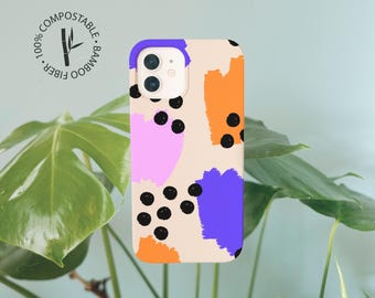 May include: A phone case with a beige background featuring abstract brushstrokes in purple, orange, and pink, accented by scattered black dots. A circular logo in the corner reads 100% COMPOSTABLE BAMBOO FIBER with a bamboo stalk illustration.