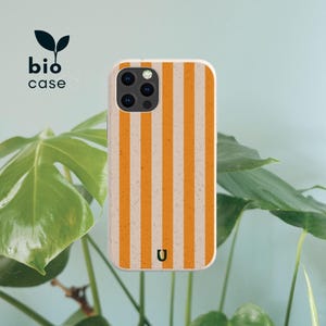 May include: A rectangular phone case featuring a vertical striped pattern in alternating shades of orange and off-white with a speckled texture. The case includes a cutout for a triple-lens camera system and a small dark green logo at the bottom.