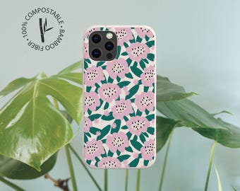 May include: A rectangular smartphone case featuring a repeating pattern of light pink flowers with dark green leaves on a cream background. The case includes a circular stamp with the text 100% COMPOSTABLE BAMBOO FIBER and a bamboo stalk icon.