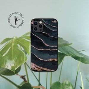 May include: A black phone case with a dark blue and gold marble design. The case has a raised camera bump and is made from 100% bamboo fiber. It is compostable.