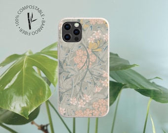 May include: A rectangular phone case featuring a muted sage green background with a repeating pattern of light pink flowers and slender green leaves. The case includes a circular logo with the text 100% COMPOSTABLE BAMBOO FIBER.