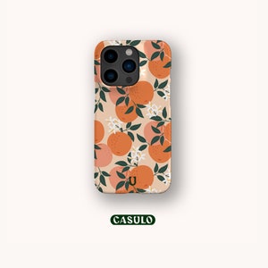 May include: A phone case with a pattern of orange slices and white flowers on a peach background. The case has a camera cutout and the letter "U" in the lower center.