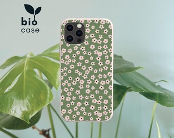 Puede incluir: Una funda de smartphone de color verde salvia con un patrón repetitivo de pequeñas flores de color rosa claro con centros oscuros. El texto "bio case" con un pequeño icono de hoja se encuentra en la esquina superior izquierda de la imagen.