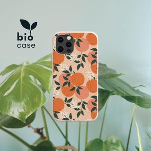 May include: A phone case with a light beige background featuring a repeating pattern of orange citrus fruits, dark green leaves, and small white blossoms. The text bio case with a small leaf icon is positioned in the upper left corner of the image.
