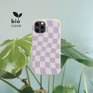 May include: A phone case with a wavy checkerboard pattern in light purple and off-white, featuring a speckled texture throughout. The case has a cutout for a triple-lens camera system. The text bio case with a leaf icon is visible.