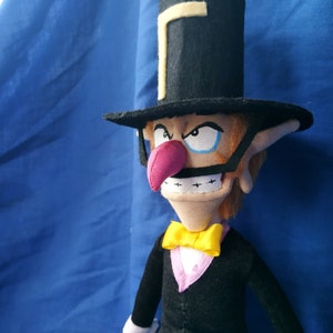 May include: A plush toy of a character wearing a black top hat with a yellow band, a black suit, and a yellow bow tie. The character has a large, red nose and a mischievous expression.