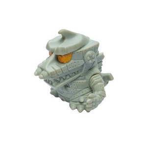 May include: A grey, stylised figurine of a robotic crocodile with orange eyes. The toy has a detailed, mechanical design with rivets and segmented armour plating. The crocodile has a drill-like snout and a fin on its head.