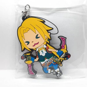 Könnte beinhalten: Ein Anime-Charakter mit gelben Haaren, einem blauen und grünen Outfit und zwei rosa und violetten Dolchen. Der Charakter ist ein Schlüsselanhänger aus Gummi.