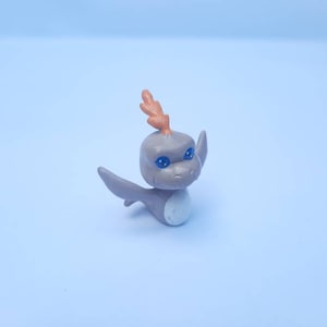 May include: A small gray and orange plastic toy dragon with blue eyes. The dragon has a white spot on its belly.