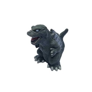 Peut inclure: Une figurine Godzilla grise et noire avec une bouche grande ouverte et des dents acérées. La figurine est posée debout, les bras levés.