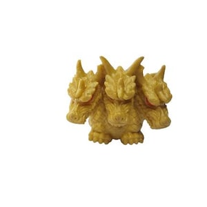May include: A three-headed golden dragon figurine with red eyes. The dragon has a textured surface and is posed in a standing position.
