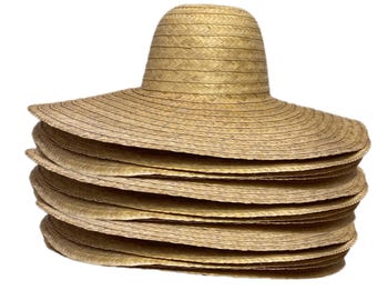 May include: A stack of wide-brimmed, natural-colored straw hats. Each hat has a rounded crown and a broad, circular brim. The hats are made of woven straw, and the stack shows the texture and layers of the hats.