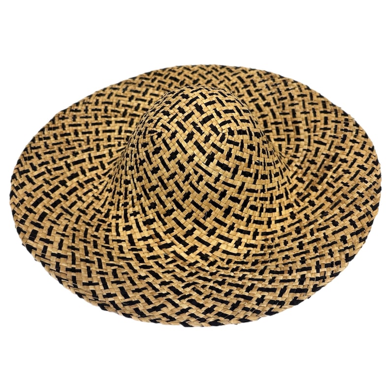May include: A wide-brimmed sun hat with a woven pattern of natural beige and black. The hat features a rounded crown and a broad, floppy brim, offering ample shade. The weave creates a textured surface, perfect for sunny days.