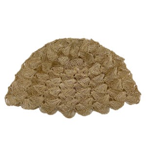 May include: A woven, beige, half-circle shaped decorative object. The object is made of tightly woven, small, cone-shaped pieces. The edges have a scalloped design. The background is white.