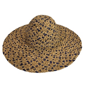 Puede incluir: Un sombrero de paja de ala ancha con un diseño tejido en marrón y azul. El sombrero tiene una corona ligeramente redondeada y un ala ancha y plana.