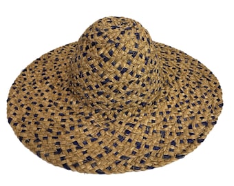 May include: A wide-brimmed straw hat with a woven design in brown and blue. The hat has a slightly rounded crown and a wide, flat brim.