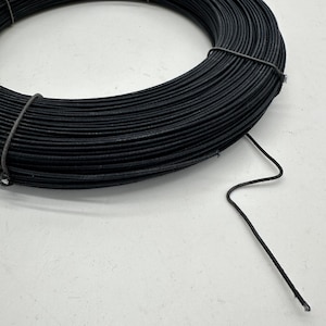 May include: A spool of black wire. The wire is wound tightly around the spool and is ready to be used for crafting or other projects.