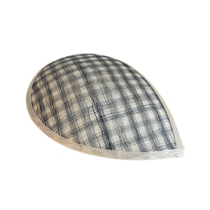 Puede incluir: Un sombrero de tela beige y negro a cuadros, de forma redondeada y ligeramente puntiaguda. El sombrero tiene un ribete beige alrededor del borde.