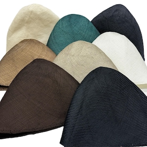 Puede incluir: Una colección de gorras de calavera de varios colores, incluyendo beige, verde, marrón, tostado, blanco y negro. Las gorras están hechas de una tela acanalada y están dispuestas en un patrón en capas, mostrando las diferentes opciones de color.