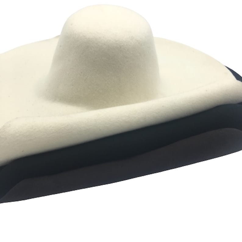 May include: A white felt fedora hat with a wide brim and a tall crown. The hat has a black band around the base of the crown.