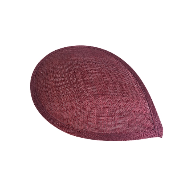 Puede incluir: Una base de sombrero de sinamay de color burdeos, un tipo de tejido utilizado para la sombrerer&iacute;a, en forma de l&aacute;grima.