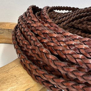 brown braided leather head band. It is made of multiple strands of leather that are woven together to create a thick, durable cord.