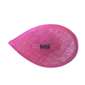 Puede incluir: Un sombrero de tela rosa con una etiqueta negra que dice "Hatroom".