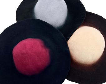 Può includere: Tre cappelli di feltro in uno scatto in studio. Uno è nero con il centro rosso, un altro è nero con il centro grigio chiaro, e il terzo è marrone scuro con il centro crema. I cappelli sono disposti in un motivo circolare.