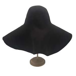 May include: A wide-brimmed black felt hat with a rounded crown. The hat is displayed on a wooden stand.