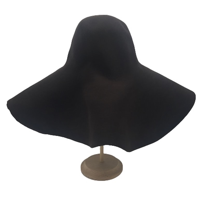May include: A wide-brimmed black felt hat with a rounded crown. The hat is displayed on a wooden stand.