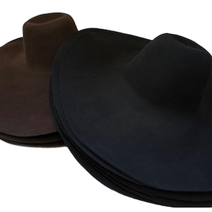 May include: Two wide-brimmed felt hats, one brown and one black. The hats are stacked on top of each other.