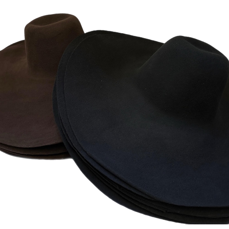 May include: Two wide-brimmed felt hats, one brown and one black. The hats are stacked on top of each other.